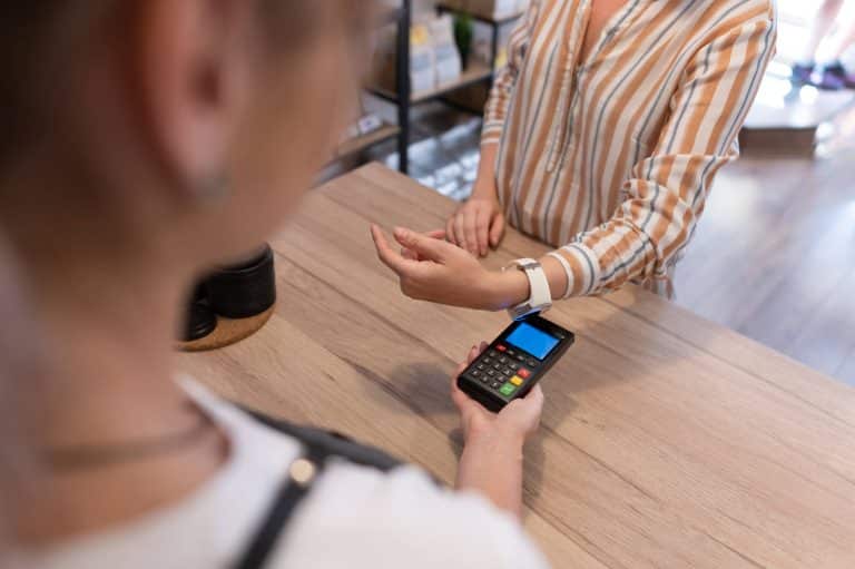 Pessoa fazendo pagamento por aproximação com smartwatch.