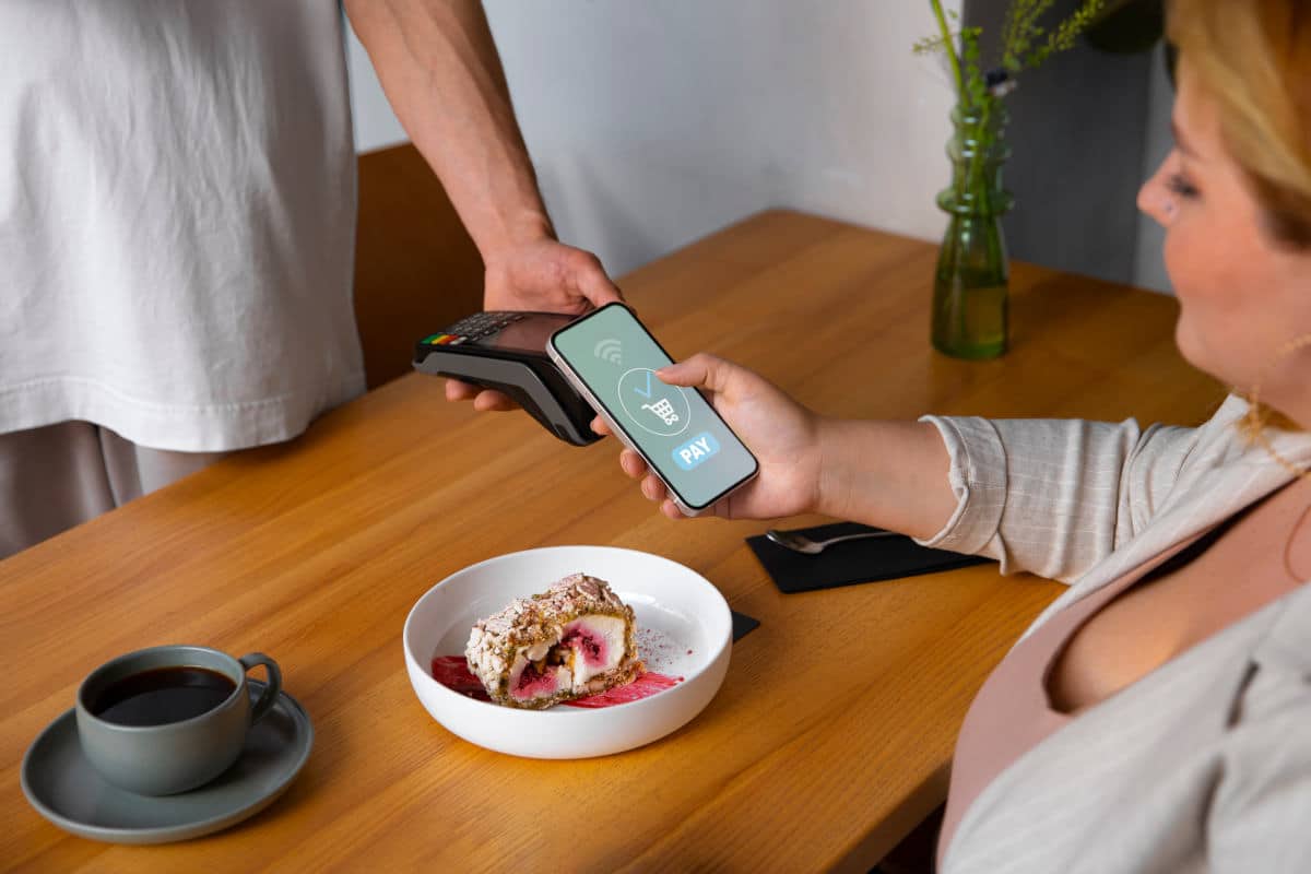 Pessoa utilizando o iPhone como terminal de pagamento por aproximação em uma venda presencial
