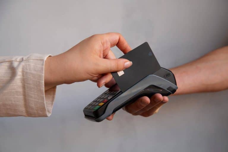 Pessoa realizando um pagamento por aproximação com um dispositivo NFC, em vista lateral.